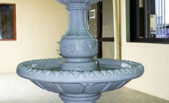 a large , ornate blue fountain with three levels of water is displayed in a room at Hotel Lewi
