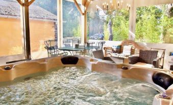 a large indoor hot tub surrounded by chairs and tables , with a view of the surrounding landscape at La Maison Rouge Broceliande