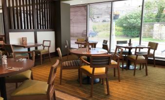a dining room with wooden tables and chairs arranged in a circle around a fireplace at Premier Inn Oban