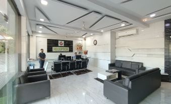 a modern office lobby with black leather couches , a marble floor , and a reception desk at Royal Garden Resort