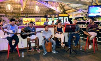 a group of people , including a man playing a guitar , are gathered at a bar , enjoying each other 's company at Discovery Inn