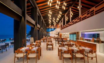 a modern restaurant with wooden tables and chairs , a bar , and a large chandelier hanging from the ceiling at The Westin Maldives Miriandhoo Resort