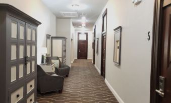 a hallway with a carpeted floor , gray cabinets , and a mirror on the wall , leading to a door at The Dilworth Inn
