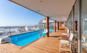 a rooftop pool area with a wooden deck and a view of the city , featuring lounge chairs and umbrellas at Artiem Capri