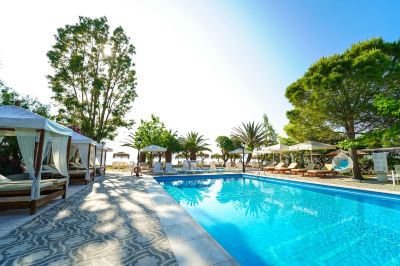 a beautiful outdoor pool area with umbrellas , sun loungers , and trees under a clear blue sky at Hotel Summery