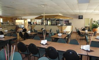 a restaurant with multiple tables and chairs , a counter , and a tv on the wall at The Lodge Motel