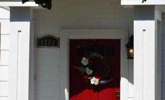 a white house with a red door and a flower arrangement in front of it at Sassafras Inn