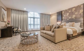 a modern living room with a beige couch , coffee table , and large window overlooking a city view at Marcian Garden Hotel