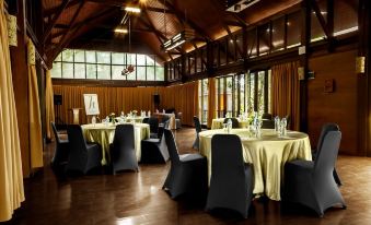 a room with several round tables and chairs , some of which are covered with yellow tablecloths at Horison Green Forest Bandung