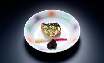 a white plate with a piece of food and a red carrot on the side at Osakaya Ryokan