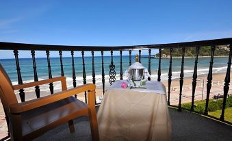 a table with a vase and pink flowers is set on a balcony overlooking the ocean at Hotel Don Pepe