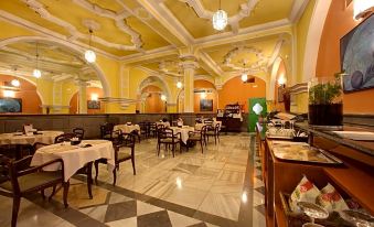 a large , elegant restaurant with yellow walls and white columns , featuring multiple dining tables and chairs at Hotel Inglaterra