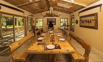 a large wooden dining table set for a meal , with several chairs surrounding it , creating a cozy atmosphere at Rocky Point Ranch