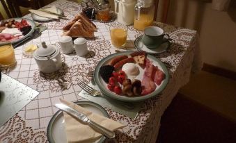 a table is set with a breakfast spread , including eggs , bacon , toast , and orange juice at Ardwell Bed & Breakfast