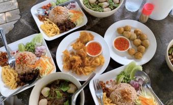 a table is filled with various dishes , including a bowl of soup and plates of rice and vegetables at BaanSuanLeelawadee Resort Amphawa