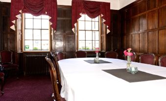 a dining room with a round table surrounded by chairs , and a vase of flowers on the table at Limes Hotel