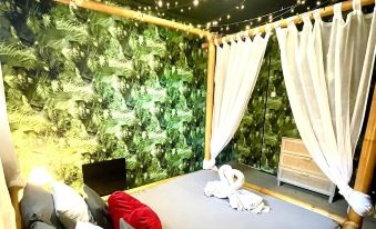 a cozy bedroom with a canopy bed , pillows , and blankets , surrounded by green walls and string lights at Lovely