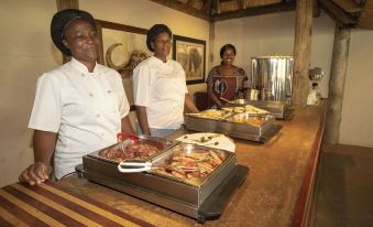 a group of women standing in line at a buffet , waiting to be served at Tembe Elephant Park