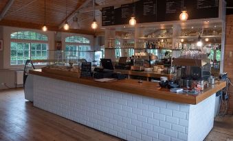 a restaurant with a long white brick counter and a menu board , featuring coffee and pastries at Trail Lodge