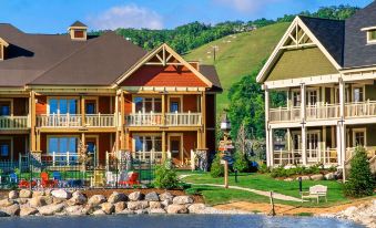 a beautiful lake with two luxury houses situated on the shore , surrounded by lush green grass and trees at Hilton Grand Vacations Club Blue Mountain Canada