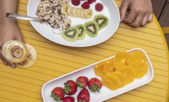 There is a plate of food with two bowls on the side, one of which contains an orange slice at Arcelon Hotel