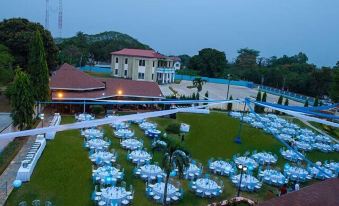 an aerial view of a large outdoor event space with multiple tables set up on a grassy area , surrounded by buildings and trees at Golden Bean Hotel