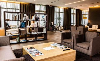 a modern living room with a wooden coffee table , couches , chairs , and a bookshelf filled with books at HSM Hotel San Martino