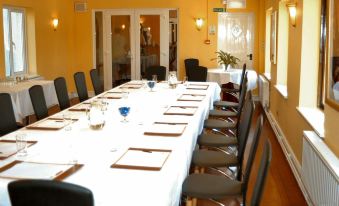 a long dining table set up for a formal dinner , with multiple chairs arranged around it at Coach House Hotel