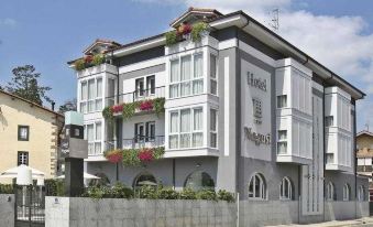 a white building with balconies and flower boxes , situated on a street corner in a city at Hotel Nagusi