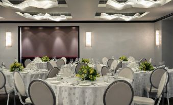 a well - decorated banquet hall with multiple round tables , each set with white tablecloths and elegant chairs at The Park Chennai