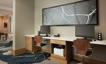 a modern office space with a large map on the wall , two computer monitors , and wooden desks at Hampton Inn & Suites Teaneck Glenpointe