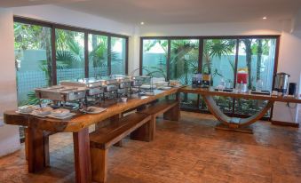 a dining area with a long wooden table covered in various dishes and utensils , creating a pleasant atmosphere at Hotel Rio Lagartos