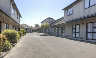 a row of empty buildings with white trim and large windows , located in a residential area at Auckland Airport Motel