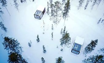 an aerial view of a snow - covered forest with three small cabins nestled in the woods at Arctic Skylight Lodge