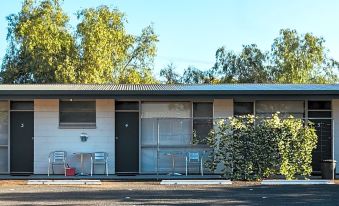 a house with a black door and white windows is surrounded by trees and bushes at Copper City Motel