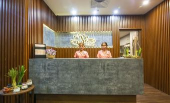 a reception desk with two women sitting behind it , wearing pink robes and a sign on the wall at Senna Hue Hotel