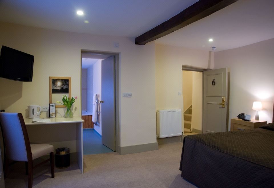 a bedroom with a bed , desk , and stairs leading to another room is shown in the image at Cartwright Hotel