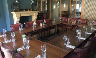 a large dining room with a long wooden table set for a formal dinner , surrounded by chairs at The White Hart