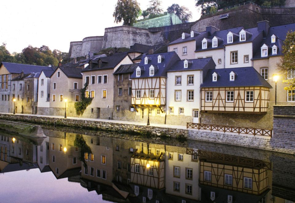 a picturesque european town with a castle on a hill , surrounded by water and buildings at Ibis Luxembourg Sud