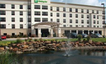 a large hotel building with a fountain in front of it , surrounded by grass and trees at Holiday Inn Carbondale-Conference Center