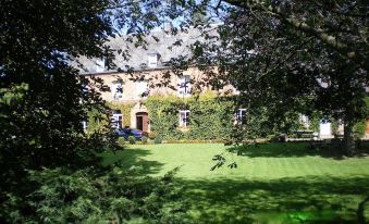 a large , green lawn with trees in the background and a building in the distance at Le Chateau