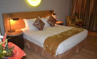 a large bed with white sheets and a gold blanket is in a hotel room at Radisson Blu Hotel, Bamako