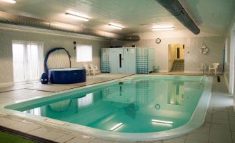 an indoor swimming pool with a blue and white striped bathtub , surrounded by white walls and a ceiling with lights at The Mansion