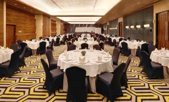 a large conference room filled with round tables and chairs , all set for a formal event at Hotel Ciputra Cibubur Managed by Swiss-Belhotel International