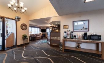 a hotel lobby with a bar , couches , and a coffee machine , under a large window at Quality Inn & Suites