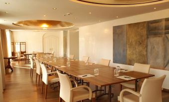 a long wooden dining table set for a large group of people , with several chairs arranged around it at Hotel des Balances