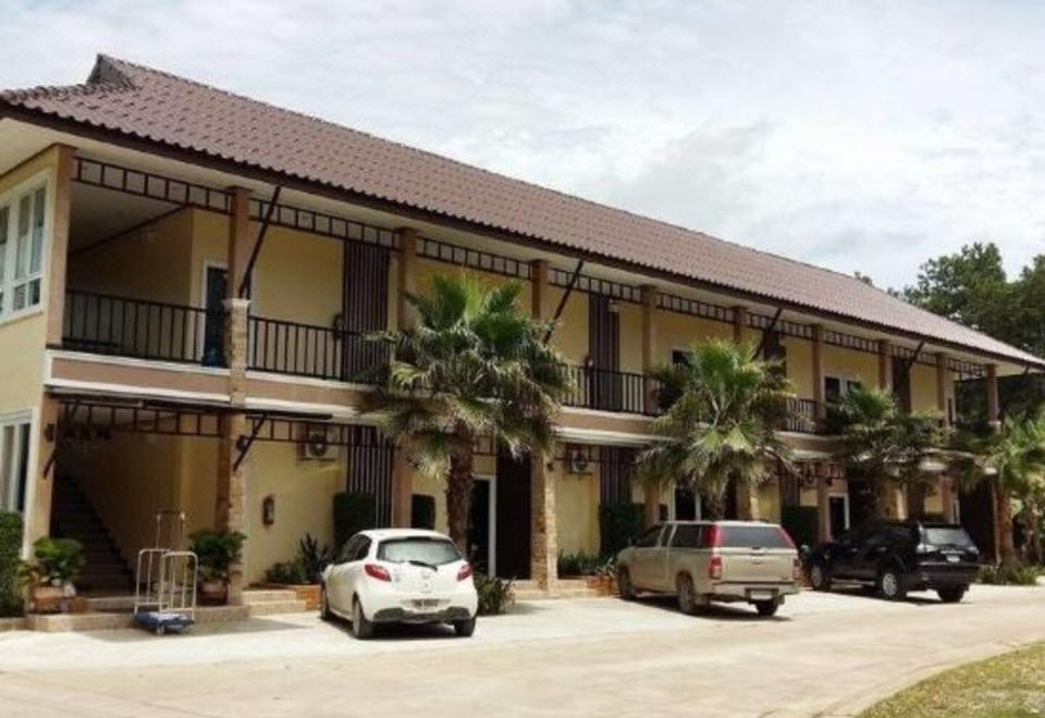 a building with a parking lot in front of it , and cars parked outside of the building at Palm Sweet Resort