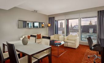 a spacious living room with a couch , chairs , and dining table is shown with large windows at Park Plaza Westminster Bridge London