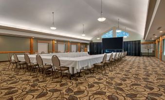 a large conference room with a long table and chairs , a projector screen , and chandeliers at Best Western Plus Valemount Inn  Suites