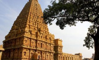 a large , ornate temple with a high spire is surrounded by a crowd of people at Sangam Hotel, Thanjavur